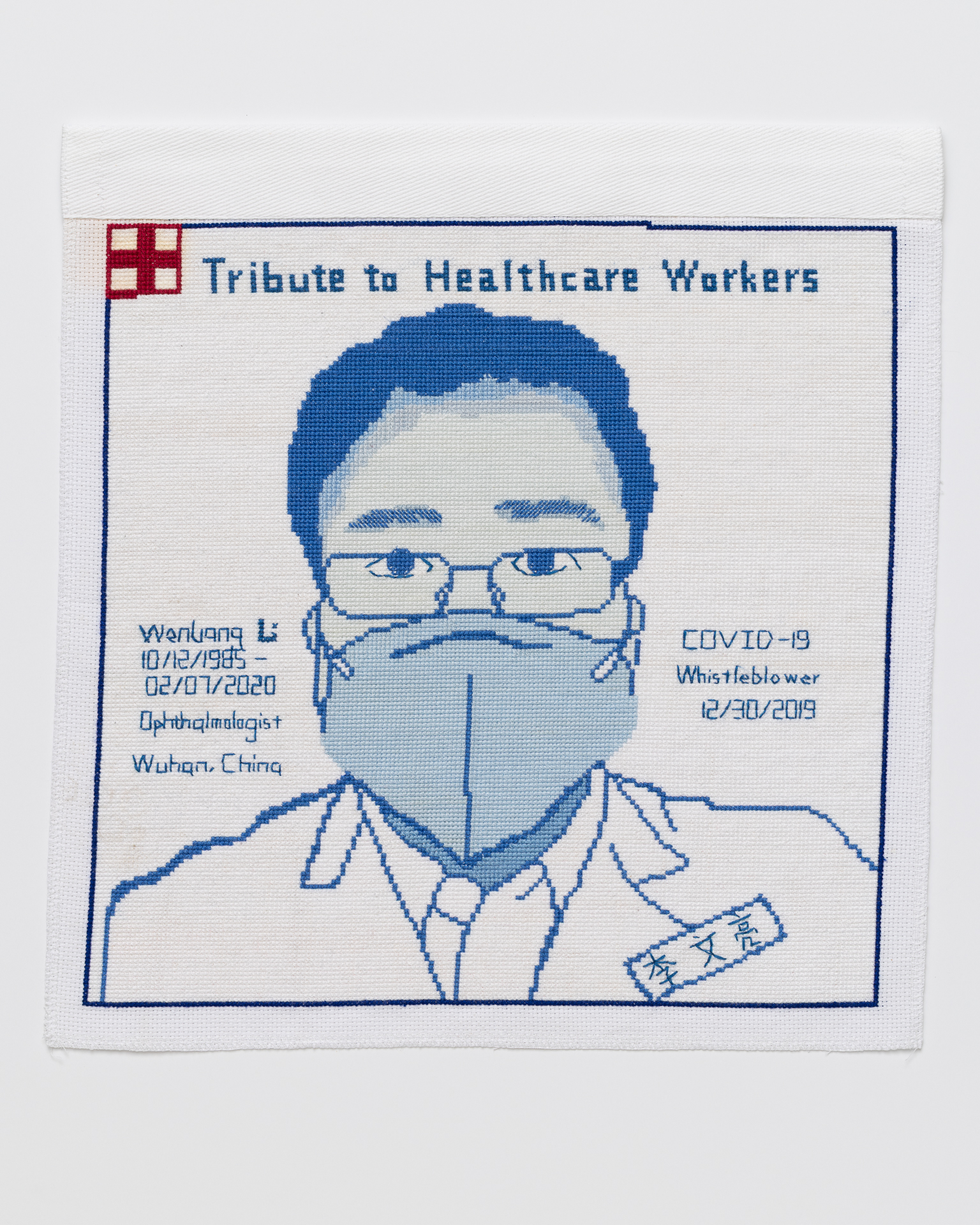 Cross stitch embroidered portrait of Dr. WenLiang Li. His name is stitched to the left of his image, along with "10/12/1985 - 02/07-2020 Ophthalmologist Wuhan China. In his portrait he is wearing thin rimmed glasses, a light blue mask, a white button down shirt and lab coat. His name is stitched in chinese on his coat. To the right of his image is written, "COVID-19 Whistleblower 12/30/2019. There is a pink square outlined in red with a red medical cross in the middle. Across the top of the image is written, "Tribute to Healthcare Workers"