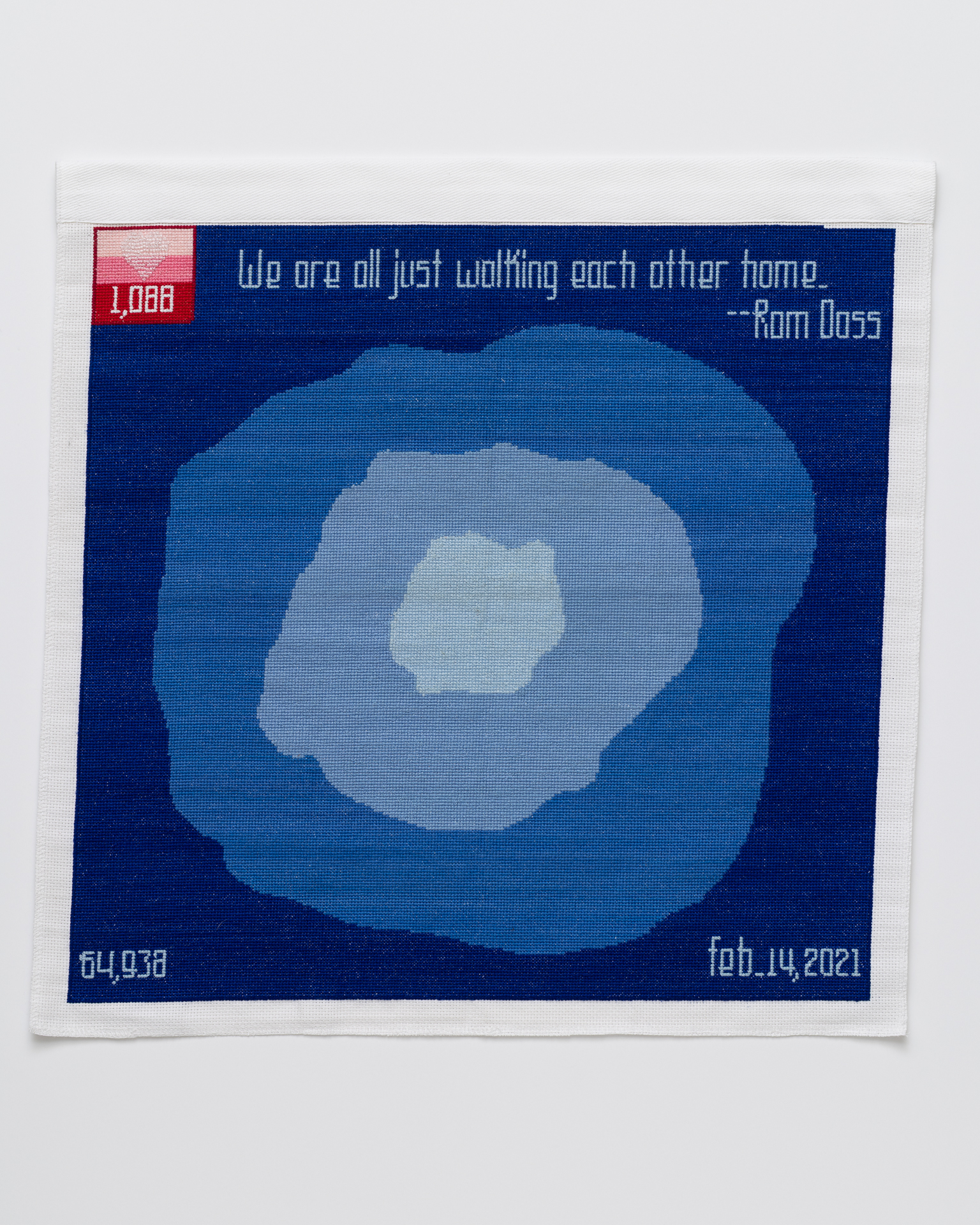 cross stitch embroidery of abstract blue splotches, with lightest blue in middle, two slightly darker, then dark blue background. There is a red square in the top left with three shades of pink with "1088" written. A heart is formed with beads over the top of the square. "We are all just walking each other home. -Rom Doss" is written across the top of the blue. "64,938" is in the bottom left corner and "feb 14, 2021" in the bottom right.