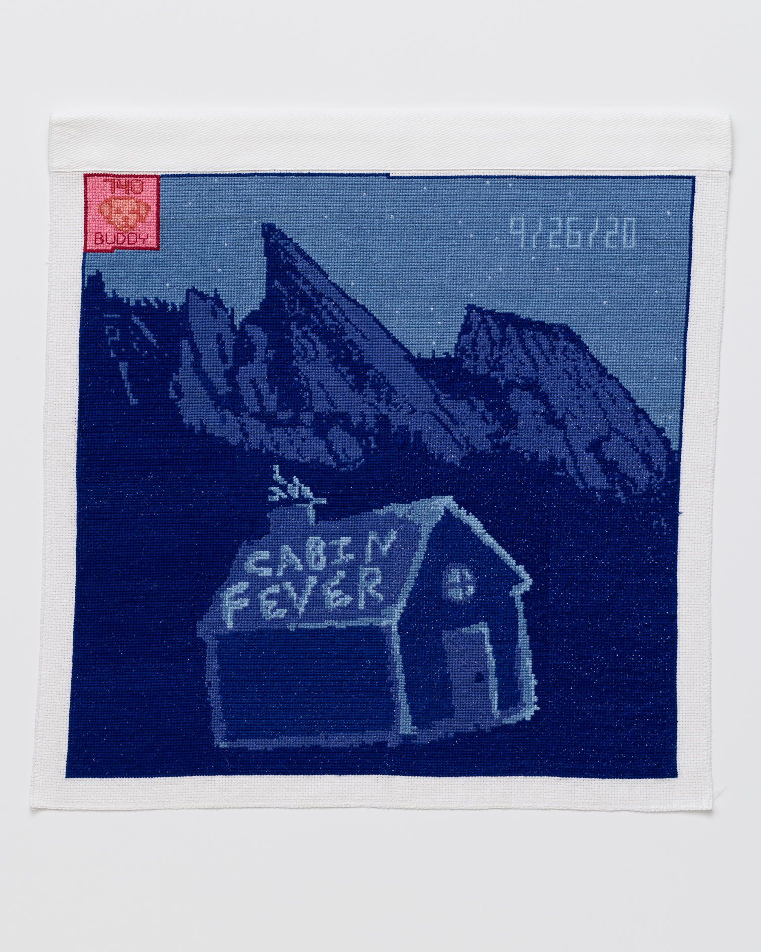 Cross stitch embroidery of small cabin at night in front of mountains. "CABIN FEVER" is written on the roof. "9/26/2020" is written in the top right. There is a pink square with a red border and an image of a dog with "740" above and "BUDDY" below.