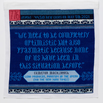 Photo by Wes Magyar (es translation) Cross stitch embroidery in blue threads with pink and red square in top left corner "776" written inside the square. The top strip of the piece reads "deaths 44, 510 new cases on may 5th 2021." below that is a pattern of scallops in dark blue, with a line of blue dots and stripes beneath it. In the middle is a quote: "we need to be completely optimistic but also pragmatic because none of us have been in this situation before." In the bottom is a light blue diamond shape with "Cameron Mackintosh Lead Producer, Phantom of the Opera (via the New York Times) written. The stripe/dot/scallop pattern is repeated at the bottom.